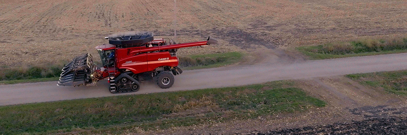 Drago corn head folded on a Case combine driving down a gravel farm road